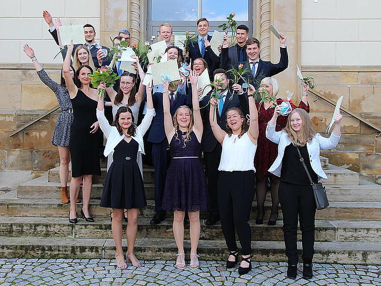 Geschafft - Absolventen mit Blumen vor Haus 1