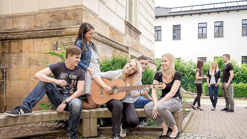 Studierende mit Gitarre vor Haus 3